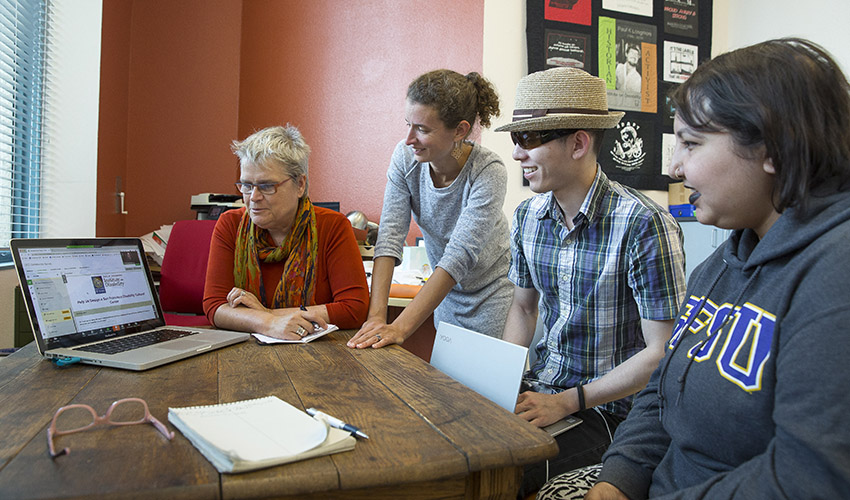 Four members of a team viewing a laptop